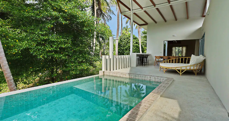 A villa with a pool with a deck and chairs 